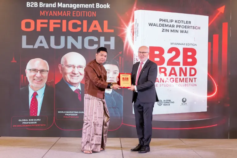 Prof. Dr. Waldemar Pfoertsch presenting an award on stage in front of the Myanmar Edition cover
